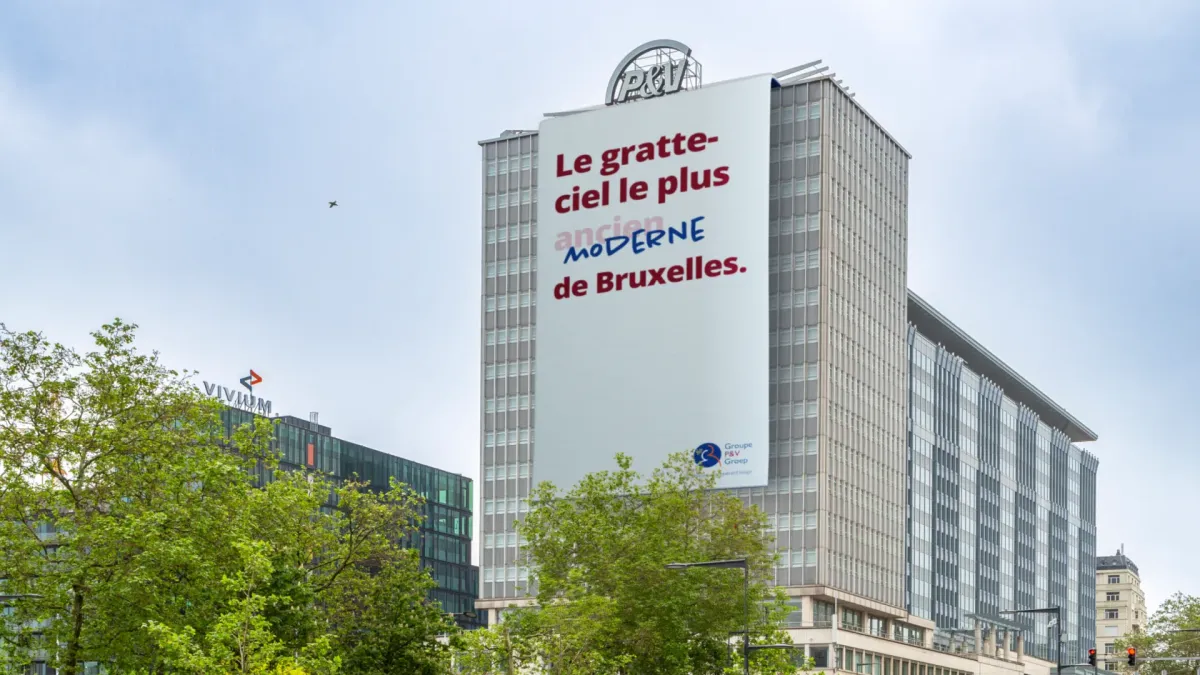 La tour P&V avec une banderole affichant le slogan « Le gratte-ciel le plus moderne de Bruxelles »